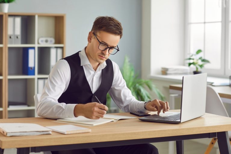 Empresário analisando relatórios financeiros e planejando como fazer um balanço do negócio no escritório.