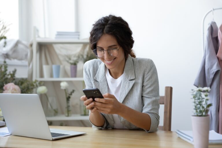 Empreendedora usando aplicativo de gestão no celular para profissionalizar um negócio e organizar tarefas.