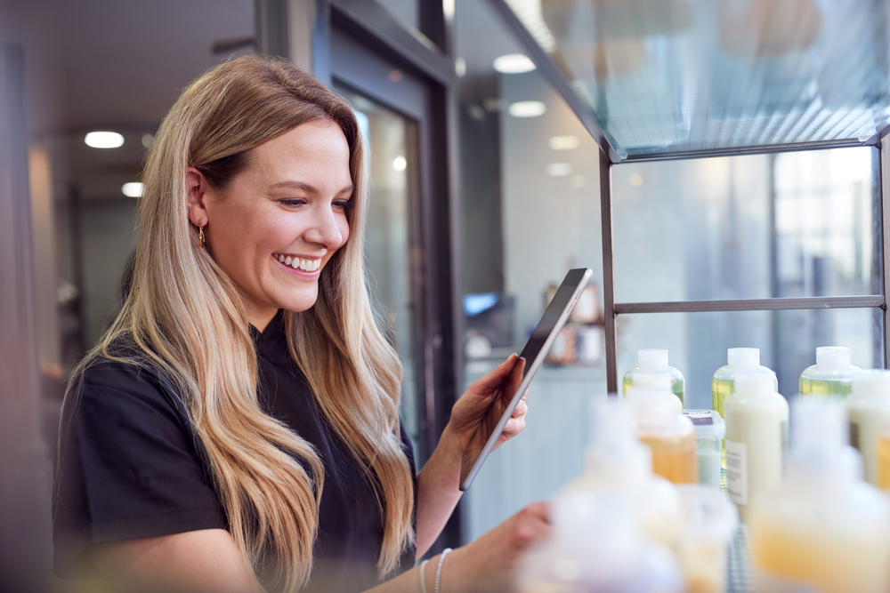 Empreendedora usando tablet para organizar produtos e evitar prejuízos com estoque no pequeno negócio.