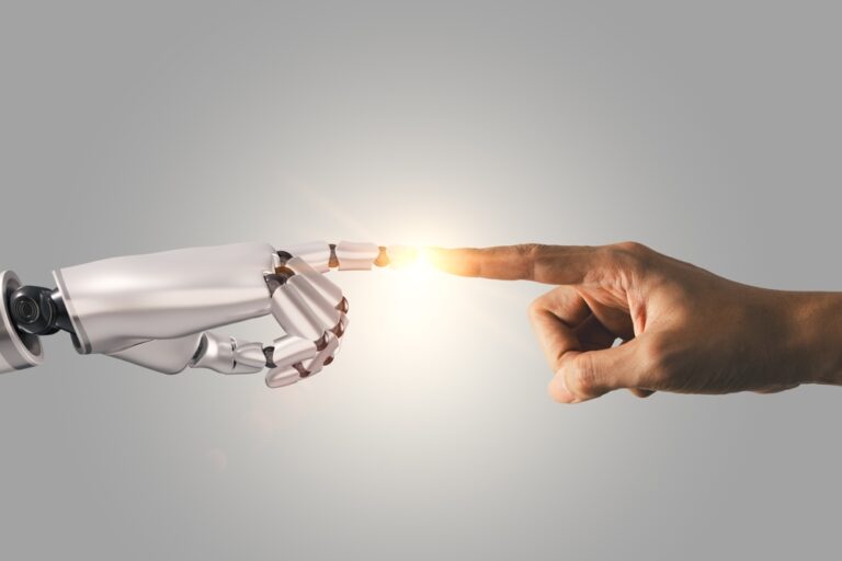 Mão humana tocando a ponta do dedo de um robô com luz entre elas, simbolizando a conexão entre pessoas e tecnologia na IA para pequenos negócios.
