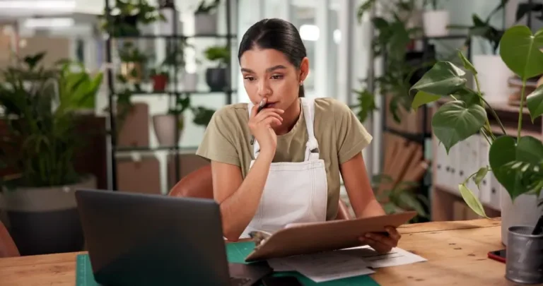 Empreendedora analisando planilhas no computador para organizar o cadastro de clientes.