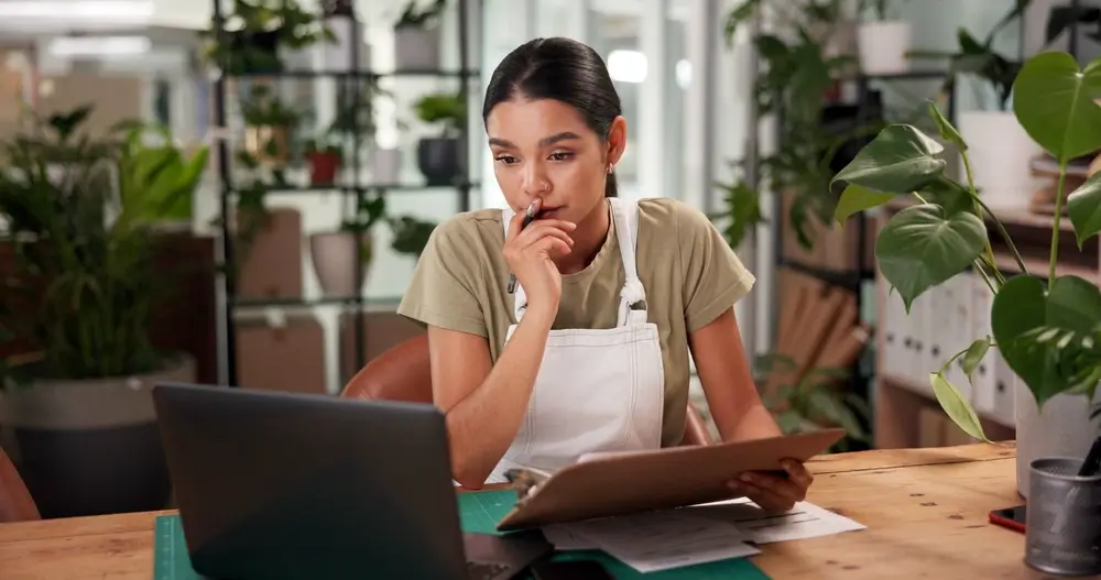 Empreendedora analisando planilhas no computador para organizar o cadastro de clientes.
